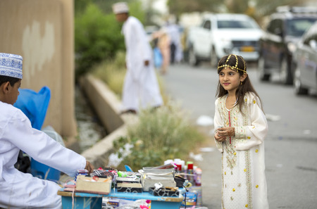 Nizwa, Oman - June 26th 2017: young lady at a toy market on a day of Eid al Fitr, celebration at the end of Holy Month of Ramadanのeditorial素材
