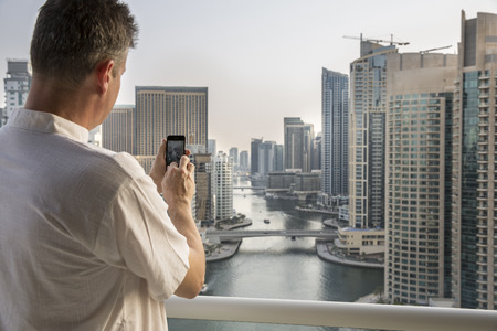 middle aged man taking picture of a marina view in Dubaiの写真素材