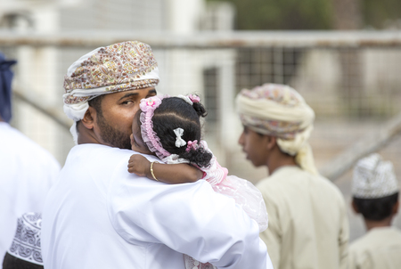 Nizwa, Oman - June 26th 2017: little Omani girl sleeping on a shoulder of her daddy at a market on a Eid Al Fitr dayのeditorial素材