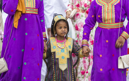Nizwa, Oman - June 26th 2017: little girl in traditional outfit, with her mother at a toy market on a day of Eid al Fitrのeditorial素材