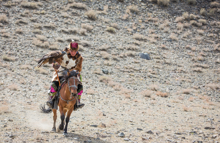 BAYAN ULGII, MONGOLIA - CIRCA OCTOBER 2015: Kazakh man in traditional clothing  with his eagle on...