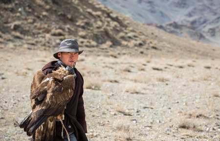 BAYAN ULGII, MONGOLIA - CIRCA OCTOBER 2015: a nomad man is walking with his eagle on his arm