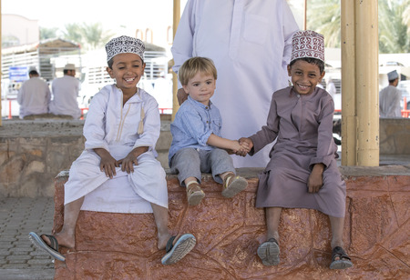 Nizwa, Oman, November 10th, 2017: omani boys with a european boy at a Friday marketのeditorial素材