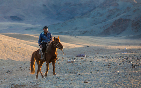 Bayan Ulgii, Mongolia, October 2nd, 2015: Man with his horse in Mongolian landscape at sunsetのeditorial素材