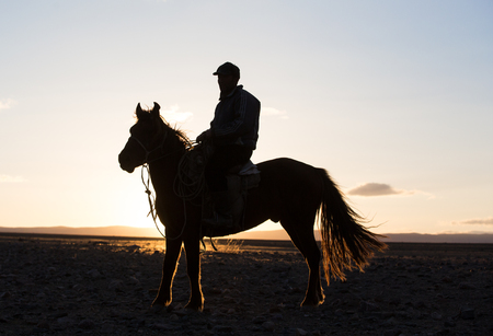 Bayan Ulgii, Mongolia, October 2nd, 2015: Man with his horse in Mongolian landscape at sunsetのeditorial素材
