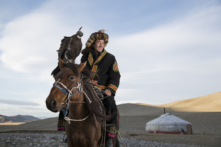 BAYAN ULGII, MONGOLIA - CIRCA OCTOBER 2015: man in traditional Kazakh clothing with his Altai Golden...