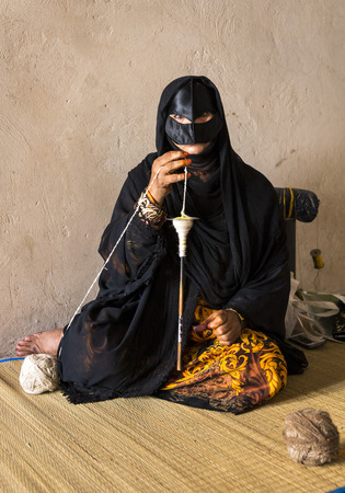 Nizwa, Oman, Febrary 2nd, 2018: old woman in full traditional outfot, spinning yarnのeditorial素材