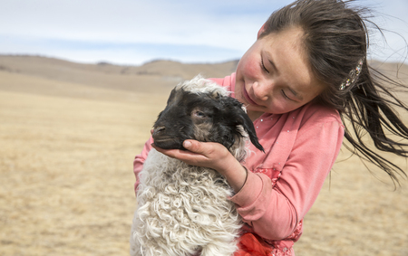 Hatgal, Mongolia, 2nd March 2018: mongolian girl carrying a baby sheep in a steppeのeditorial素材