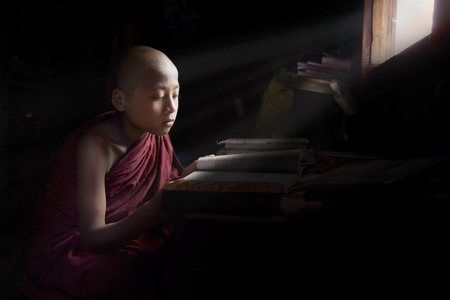 Yangon, Myanmar - 16 November, 2014: young novice monk studying next to a windowのeditorial素材