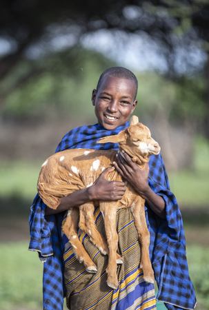 same, Tanzania, 4th June 2019: maasai boy with a baby goatのeditorial素材