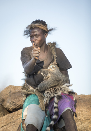 Lake Eyasi, Tanzania, 11th September 2019: Hadzabe young man in animal fir clothing, resting