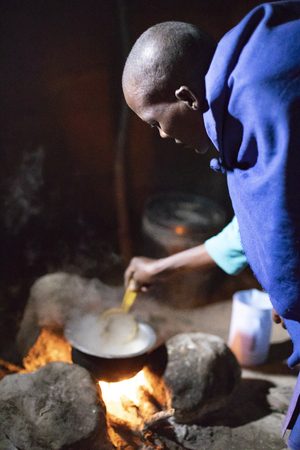 Same, Tanzania, 5th June, 2019:  Maasai woman making tea inside her kitchenのeditorial素材