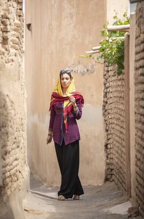 young beautiful iranian lady on the streets of an old village in Iranの写真素材