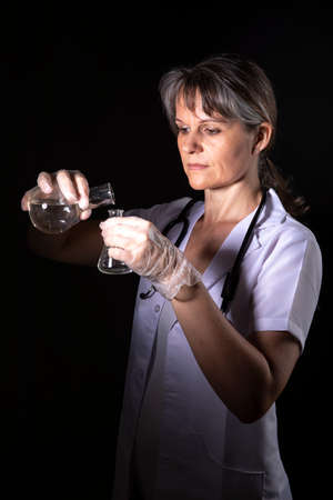 woman pouring liquid into a lab flask