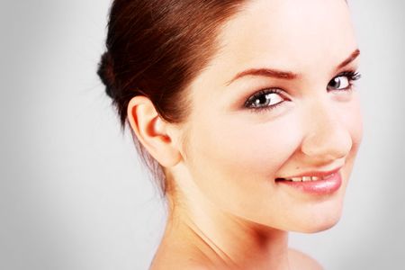 A close up of a beautiful smiling woman in front of a gray background.の写真素材