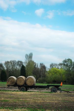 Hay bales trailer in a field with blue cloudy skyの写真素材