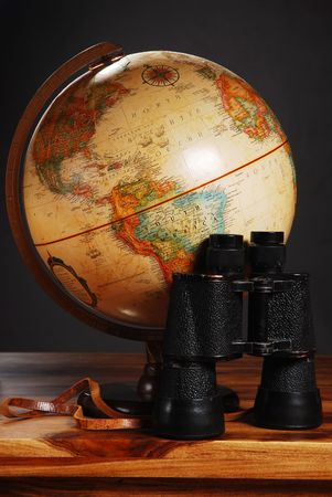Antique Globe and Binoculars on a table, dark backgroundの写真素材