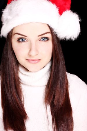 A pretty young woman wearing a santa hat on a black background.の写真素材