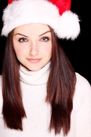A pretty young woman wearing a santa hat on a black background.の写真素材