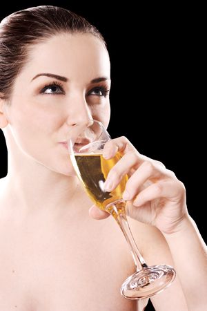 A pretty young woman drinking champagne in front of a black background.の写真素材