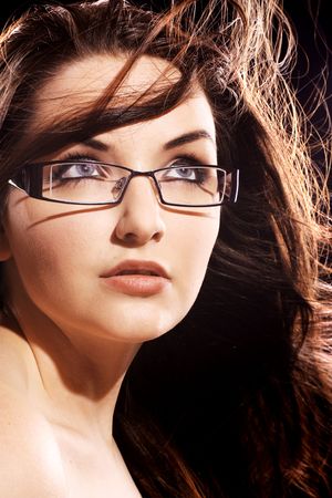 A beautiful young woman wearing fashionable glasses with her hair in motion.の写真素材