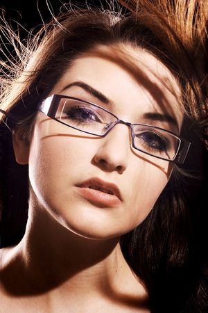 A beautiful young woman wearing fashionable glasses in front of a black background.の写真素材