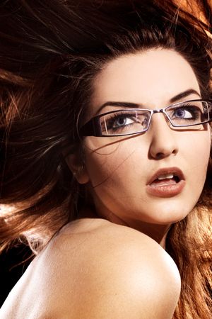 A beautiful young woman wearing fashionable glasses with her hair in motion.の写真素材