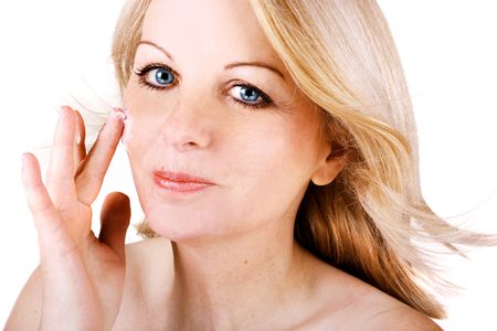 A beautiful middle aged woman applying cream to her face.の写真素材