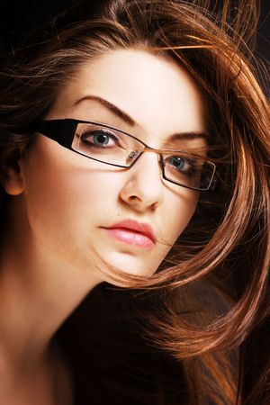 A pretty young woman wearing modern glasses with wind in her hair.の写真素材