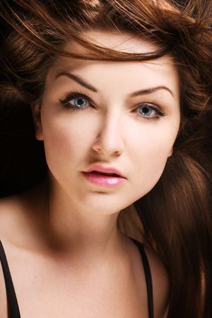 A beauty shot of a young blue eyed woman with her brown hair flowing in the wind.の写真素材