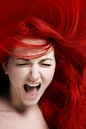A furious young woman with her hair red like fire.の写真素材