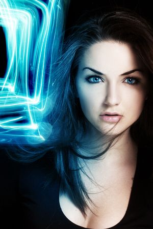 A pretty young woman with an illuminous blue light near her face. Surreal portrait.の写真素材