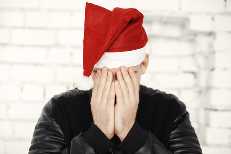 Man in red santa hat closing face with handsの写真素材