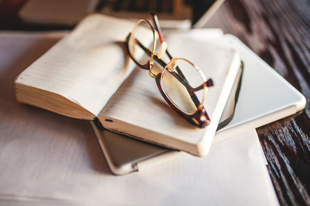 Business woman in glasses indoor with coffee and laptop taking notes in restaurantの写真素材