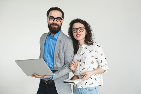 Young hipster man and woman in glasses with laptop and tablet isolated on the blank white background
