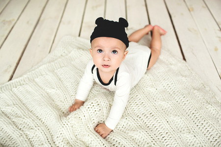 Small cute baby boy in toddler and mouse hat on rustic wooden floor