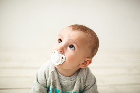 One year old cute baby boy sitting on rustic wooden floor over white の写真素材