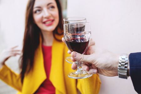 Young woman clinking red wine glass with man outdoorsの写真素材