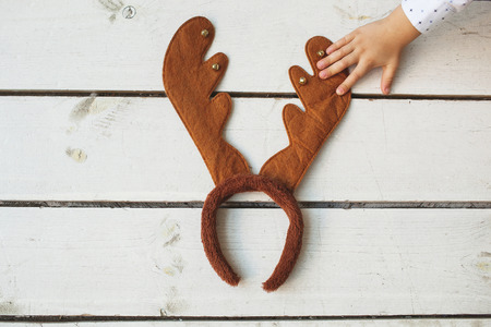 Child put hand on toy deer hornsの写真素材