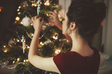 Holidays celebration  woman in red dress over christmas tree backgroundの写真素材