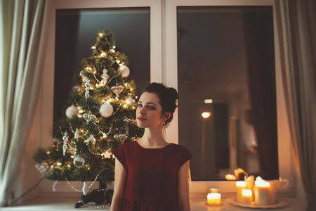 Holidays celebration - woman in red dress over christmas tree backgroundの写真素材