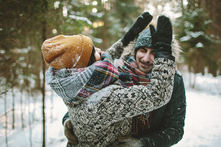 Young hipster couple having fun in winter forestの写真素材
