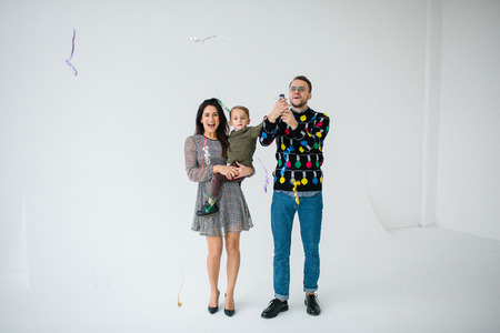 Young family of mother father and son celebrating with confetti over white backgroundの写真素材