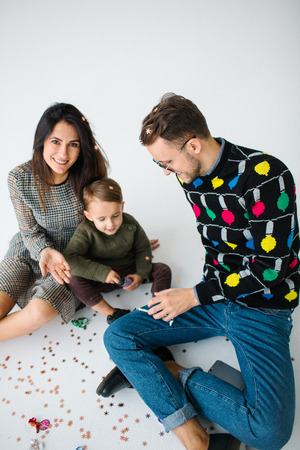 Young family of mother father and son celebrating with confetti over white backgroundの写真素材