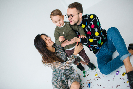 Young family of mother father and son celebrating with confetti over white backgroundの写真素材