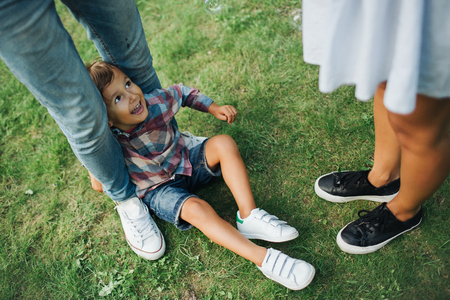 Legs of man woman and child on green grass outdoorsの写真素材