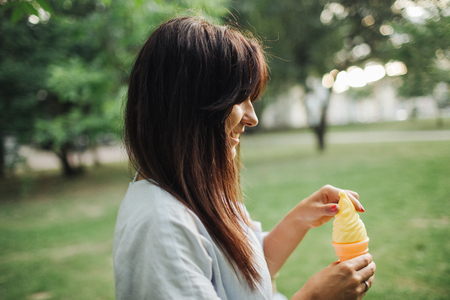 Young caucasian woman with ice cream in park outdoors in summerの写真素材