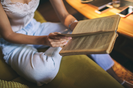 Young pretty skinny caucasian woman reading book in loft cafe wearing eyeglassesの写真素材