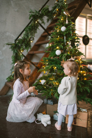 Two little cute sisters decorating green Christmas tree at homeの写真素材