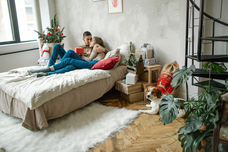 Young caucasian couple unboxing presents laying on bed at homeの写真素材